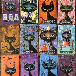 May include: A set of 12 tarot cards featuring black cats with different expressions and backgrounds. Each card has a title, such as "Ancestors", "Antzy", "Bats in Belfry", "Bubble Bath", "Bugged", "Connected", "Egg", "Elevated", "Explorers", "Eyes n Ears", "Fisher King", and "Fog".