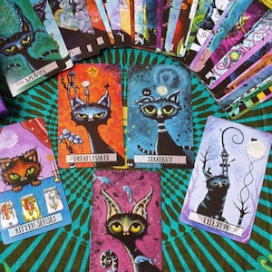 May include: A set of colorful tarot cards featuring whimsical illustrations of cats with various names, such as "Dream Maker", "Starlight", "Kitten Senses", "Telescope", and "Evolve".
