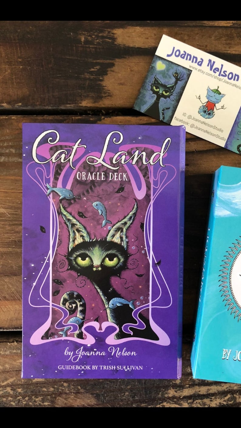 May include: Purple and pink oracle deck box with a black cat illustration and the text "Cat Land Oracle Deck" and "by Joanna Nelson".