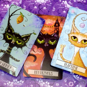 May include: Three illustrated cards featuring whimsical cats with different expressions and backgrounds. The first card shows a black and green cat with a honey pot and bees, titled "Honey Honey". The second card shows a black cat with a spooky house in the background, titled "Rendezvous". The third card shows an orange and white cat with a toy mouse, titled "Playtime".