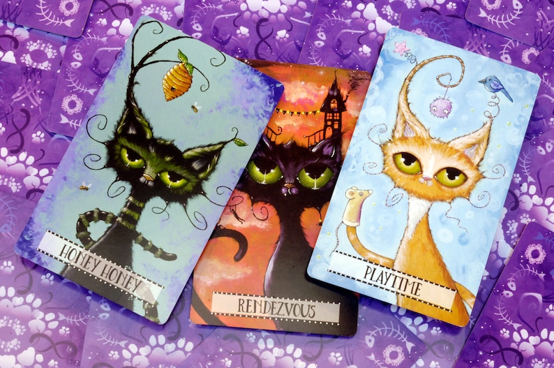 May include: Three illustrated cards featuring whimsical cats with different expressions and backgrounds. The first card shows a black and green cat with a honey pot and bees, titled "Honey Honey". The second card shows a black cat with a spooky house in the background, titled "Rendezvous". The third card shows an orange and white cat with a toy mouse, titled "Playtime".