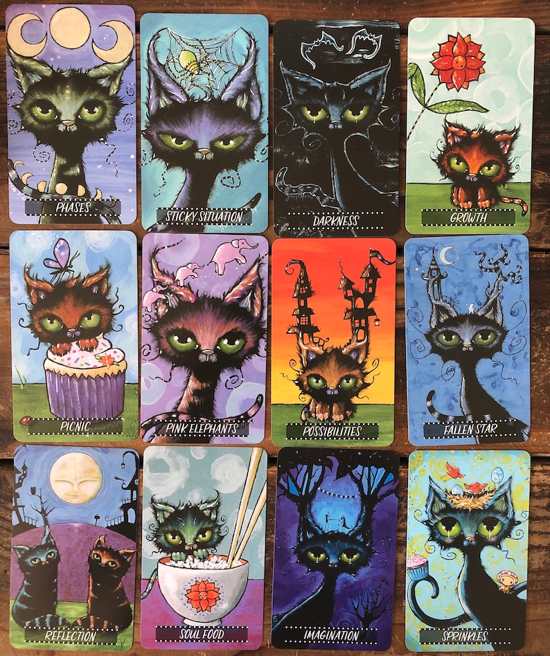 May include: A set of 12 tarot cards featuring black cats with different expressions and backgrounds. The cards are illustrated with colorful, whimsical designs and include phrases like "Phases", "Sticky Situation", "Darkness", "Growth", "Picnic", "Pink Elephants", "Possibilities", "Fallen Star", "Reflection", "Soul Food", "Imagination", and "Sprinkles".