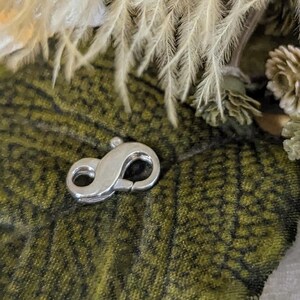 May include: Silver-toned lobster clasp for jewelry making. The clasp is a simple, functional design with a smooth finish.