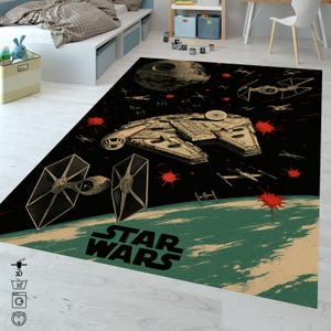 Puede incluir: Una alfombra temática de Star Wars con un fondo negro, que presenta ilustraciones del Halcón Milenario, cazas TIE y la Estrella de la Muerte. La alfombra tiene un diseño de planeta verde y beige en la parte inferior con las palabras "STAR WARS".