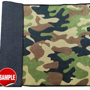 May include: A camouflage fabric sample with a black border. The fabric has a green, brown, and black camouflage pattern. The word "SAMPLE" is printed in red on a white sticker.