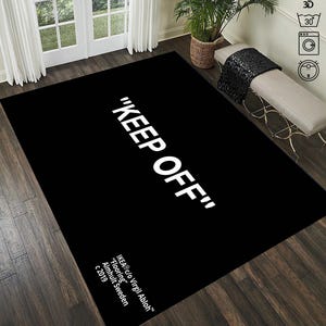 Puede incluir: Alfombra negra y blanca con el texto "KEEP OFF" en letras blancas. La alfombra tambi&eacute;n incluye el texto "IKEA&reg;c/o Virgil Abloh&trade;" "Flooring" "Almhult Sweden" "c 2019" en letras blancas.