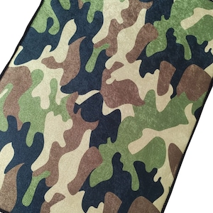 May include: A camouflage fabric with a black border. The fabric has a textured, fuzzy surface. The word "SAMPLE" is printed in white on a red circle.