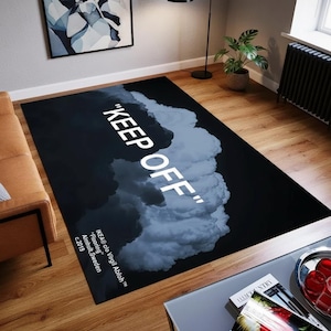 Può includere: Un tappeto rettangolare nero con la scritta bianca "KEEP OFF". Un motivo a nuvola in grigio e bianco occupa il lato destro. Il tappeto presenta il testo: "IKEA clo Virgil Abloh Flooring Almhult, Sweden c.2019".