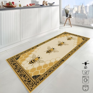 May include: A rectangular kitchen rug with a cream background, featuring a honeycomb pattern and large bee illustrations. The rug has a decorative black and gold border. The rug is placed on a white tile floor.