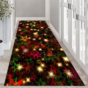 Op de afbeelding: Een zwarte en rode kerstmat met een patroon van sterren en lichtjes. De sterren zijn in tinten rood, groen, geel en goud.