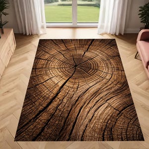 May include: A rectangular area rug with a detailed wood grain design. The rug features concentric circles and cracks, mimicking a cross-section of a tree trunk. The color palette is primarily brown and tan, creating a natural, rustic aesthetic.