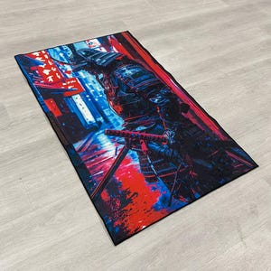 May include: A colorful rug with a samurai warrior in black armor standing in a red and blue cityscape. The warrior is holding a sword and is looking to the left.