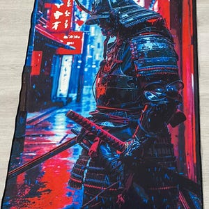 May include: A blue and red digital art print of a samurai warrior standing in a city street. The samurai is holding a katana sword and wearing traditional armor. The background is a blurred cityscape with Japanese characters.