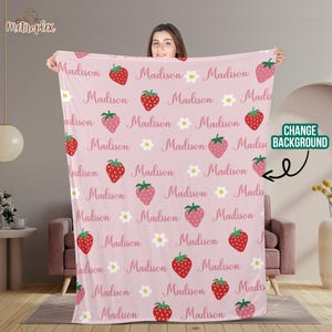 Może przedstawiać: R&oacute;żowy koc polarowy z powtarzającym się wzorem truskawek i białych kwiat&oacute;w. Imię "Madison" jest powtarzane w całym wzorze.