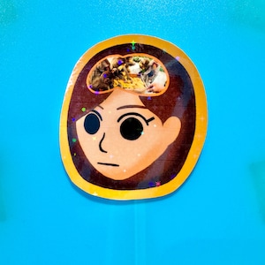 May include: A cartoon sticker of a person with brown hair and a neutral expression. The person's head is transparent, revealing a group of people in a photo.