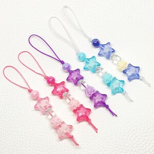 May include: A collection of colorful star-shaped beaded charms in pink, purple, blue, and clear. Each charm features a loop for hanging and is adorned with various beads and crystal accents. The charms are ideal for accessories.