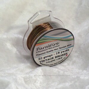 May include: A spool of 22 gauge vintage bronze wire with a copper core. The wire is 15 yards long and is a premium quality non-tarnish wire. The spool is labeled "ParaWire" and is a Paramount Wire product.