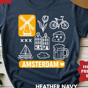 Heather navy t-shirt with white graphic icons of a windmill, tulips, bicycle, houses, cheese, beer, and a sailboat. The word "AMSTERDAM" is in orange.