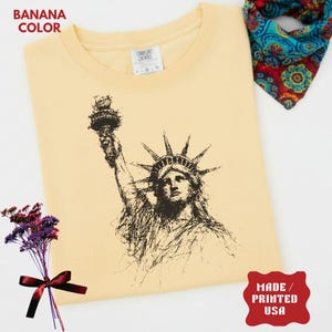 Statue of Liberty graphic t-shirt featuring a patriotic vintage-style New York design, perfect for American pride and freedom lovers.