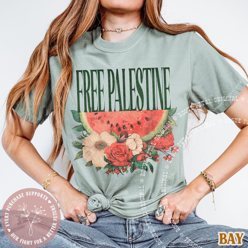 May include: Sage green t-shirt with the text "FREE PALESTINE" in dark green. The shirt features a watermelon slice and floral design in red, white, and beige. The shirt is knotted at the waist.