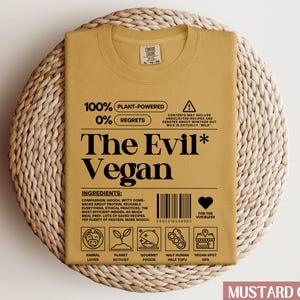 May include: Mustard yellow t-shirt with a black graphic that reads "100% Plant-Powered 0% Regrets The Evil* Vegan". The graphic also includes a barcode, a heart with the text "For the voiceless", and a series of icons representing animal lover, planet activist, gourmet foodie, half human half tofu, and vegan spot gps.
