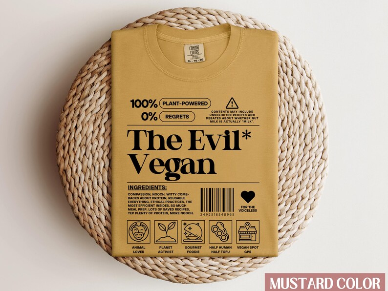 May include: Mustard yellow t-shirt with a black graphic that reads "100% Plant-Powered 0% Regrets The Evil* Vegan". The graphic also includes a barcode, a heart with the text "For the voiceless", and a series of icons representing animal lover, planet activist, gourmet foodie, half human half tofu, and vegan spot gps.
