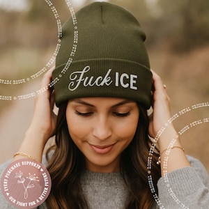 May include: Olive green beanie with the text "Fuck ICE" in white script. The hat is a knit style and is being worn. The image also includes a circular graphic with text that reads "Every purchase supports our fight for a better future."