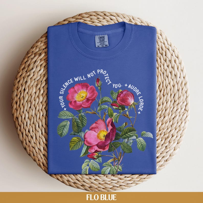 May include: A blue t-shirt with a floral design and the text "Your silence will not protect you. - Audre Lorde".