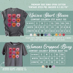 Puede incluir: Una camiseta gris oscuro de manga corta con una cuadr&iacute;cula de nueve flores de pensamiento coloridas en el pecho. La imagen incluye dos tablas de tallas para estilos unisex y cortos, con medidas en pulgadas para las tallas S a 4XL.