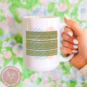 May include: White ceramic mug with a decorative design of green and blue lines and shapes. The mug has a handle and is held by a person. The mug has the text "ROGUE PETAL ORIGINAL" and "EVERY PURCHASE SUPPORTS OUR FIGHT FOR A BETTER FUTURE".