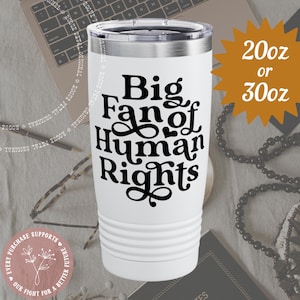 May include: White insulated tumbler with a silver lid, featuring the text "Big Fan of Human Rights" in black. The tumbler is available in 20oz or 30oz sizes. The design includes a decorative floral emblem.