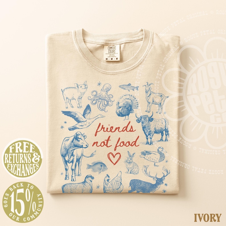 Puede incluir: Camiseta de color marfil con una ilustraci&oacute;n azul de varios animales y el texto rojo "friends not food". El dise&ntilde;o incluye un s&iacute;mbolo de coraz&oacute;n. La camiseta tiene una etiqueta Comfort Colors.