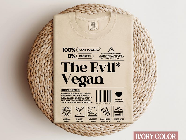 May include: A beige t-shirt featuring a graphic design that reads "100% Plant-Powered 0% Regrets The Evil* Vegan". The graphic includes a barcode, a heart with the text "For the voiceless", and icons representing animal lover, planet activist, gourmet foodie, half human half tofu, and vegan spot GPS.