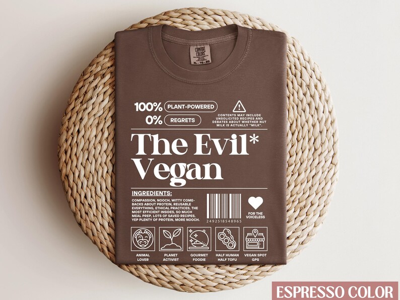 May include: Espresso brown t-shirt with a white graphic that reads "100% Plant-Powered 0% Regrets The Evil* Vegan" with a barcode and icons representing animal lover, planet activist, gourmet foodie, half human half tofu, and vegan spot GPS.