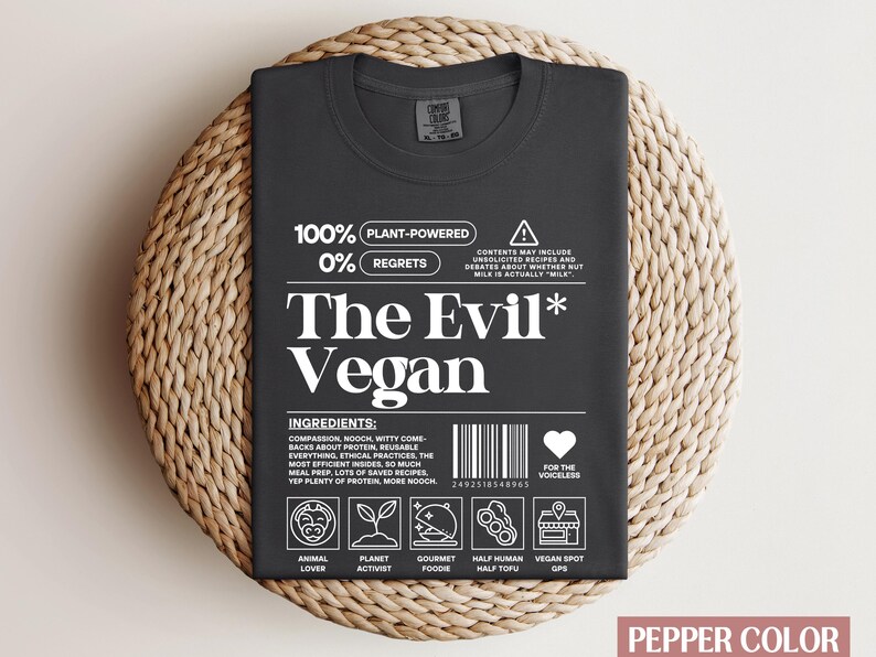 May include: Black t-shirt with white text that reads "100% Plant-Powered 0% Regrets The Evil* Vegan". The shirt has a graphic of a barcode, a heart with the text "For the Voiceless", and a series of icons representing different aspects of veganism.