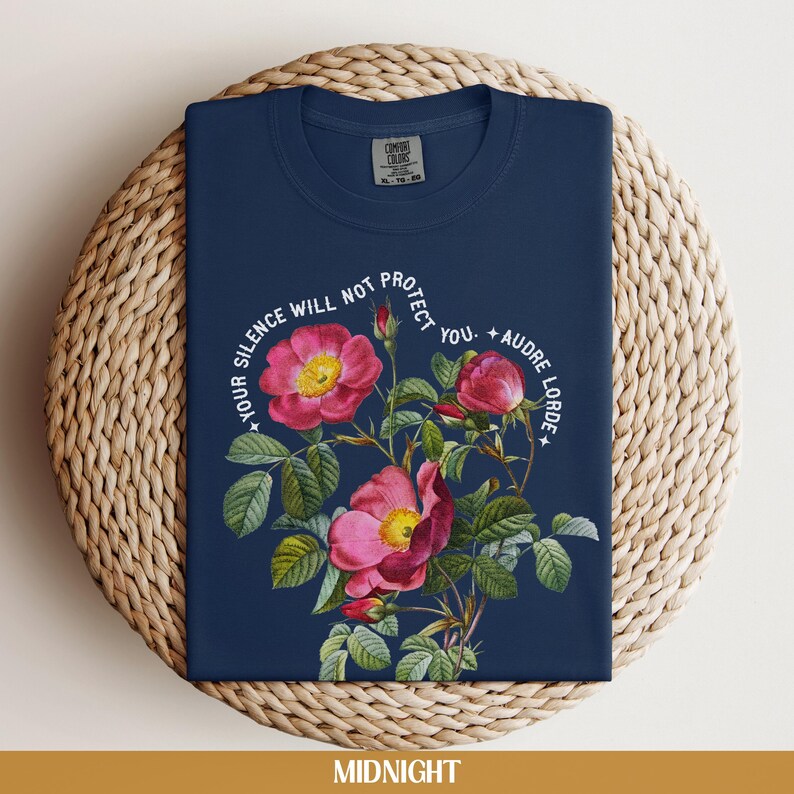 May include: A navy blue t-shirt with a floral design and the text "Your silence will not protect you. - Audre Lorde".