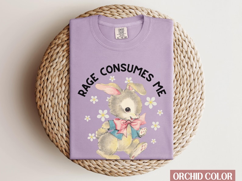Op de afbeelding: Een paars T-shirt met een cartoonkonijn en de tekst "Rage Consumes Me" erop gedrukt.