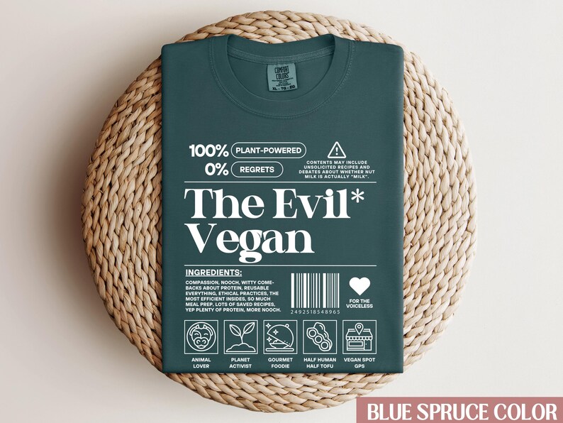 May include: A dark green t-shirt featuring a white graphic that reads "The Evil* Vegan" with a plant-powered and zero regrets message. The graphic also includes a barcode, a heart with the text "For the voiceless", and icons representing animal lover, planet activist, gourmet foodie, half human half tofu, and vegan spot GPS.