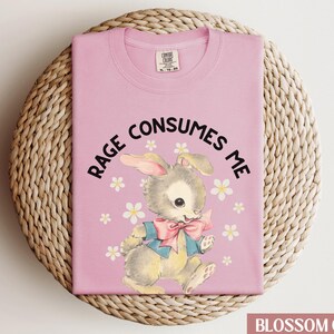 Op de afbeelding: Roze T-shirt met een afbeelding van een konijn en de tekst "Rage Consumes Me".