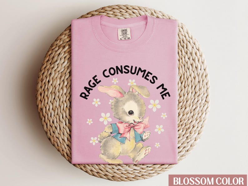 Op de afbeelding: Roze T-shirt met een afbeelding van een konijn en de tekst "Rage Consumes Me".