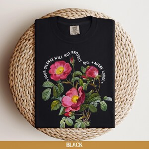 May include: Black t-shirt with a floral design and the quote "Your silence will not protect you. - Audre Lorde" printed in white.