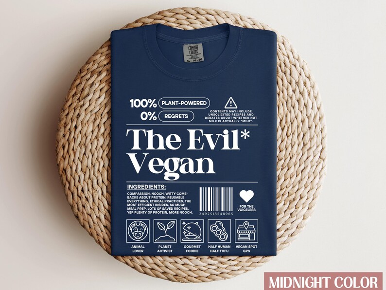 May include: A navy blue t-shirt with white text that reads "100% Plant-Powered 0% Regrets The Evil* Vegan". The shirt has a barcode and a heart with the text "For the Voiceless".