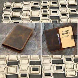 Puede incluir: Una cartera de cuero marrón, de aproximadamente 10 cm x 16 cm, se muestra abierta y cerrada. La cartera abierta revela un cuaderno "Field Notes". En el fondo hay formas troqueladas de madera.