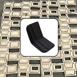 May include: A black bifold wallet with a smooth surface and rounded corners, featuring a central fold and a rectangular flap closure. The wallet is displayed against a background of numerous wooden die-cutting templates for leather goods.