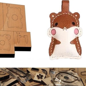 May include: A set of leather craft cutting dies featuring a cartoon hamster design. The dies are made of wood and metal and are used to cut out shapes from leather. The set includes a variety of dies, including a die for the hamster's body, head, ears, and eyes. The dies are shown on a white background.