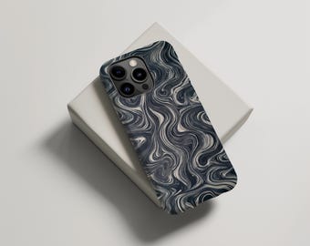 Puede incluir: Una funda para smartphone con un diseño abstracto y ondulado en tonos azul marino, gris y blanco. La funda está sobre una caja rectangular blanca, creando una estética moderna y minimalista. La funda tiene un módulo de cámara con tres lentes.