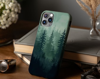 Puede incluir: Una funda para teléfono con una escena de bosque impresa. La funda es negra y tiene un diseño de acuarela verde y azul de árboles en un bosque brumoso. La funda tiene un recorte para una cámara de triple lente.