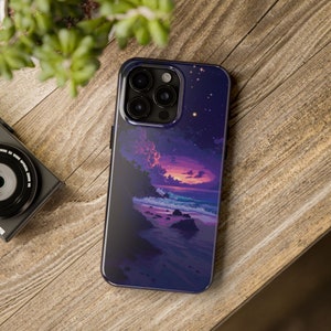 Op de afbeelding: Een paarse en blauwe telefoonhoes met een zonsondergangscène boven een strand. De hoes heeft een camera-uitsparing en een sterrenhemel.