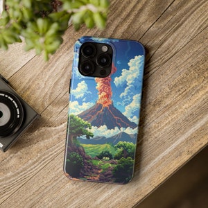 Op de afbeelding: Een telefoonhoesje met een levendige illustratie van een vulkaanuitbarsting. Het ontwerp toont een gedetailleerd landschap met groene bomen, een pad en een blauwe lucht met wolken. De hoes ligt op een houten oppervlak.