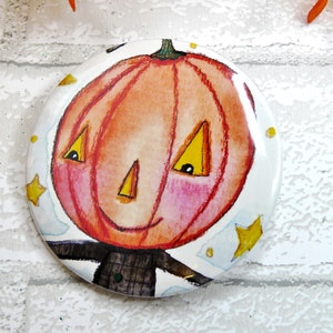 May include: A round, white, ceramic magnet with a cartoon illustration of a smiling pumpkin with a black stem and yellow eyes. The pumpkin is surrounded by white clouds and yellow stars.